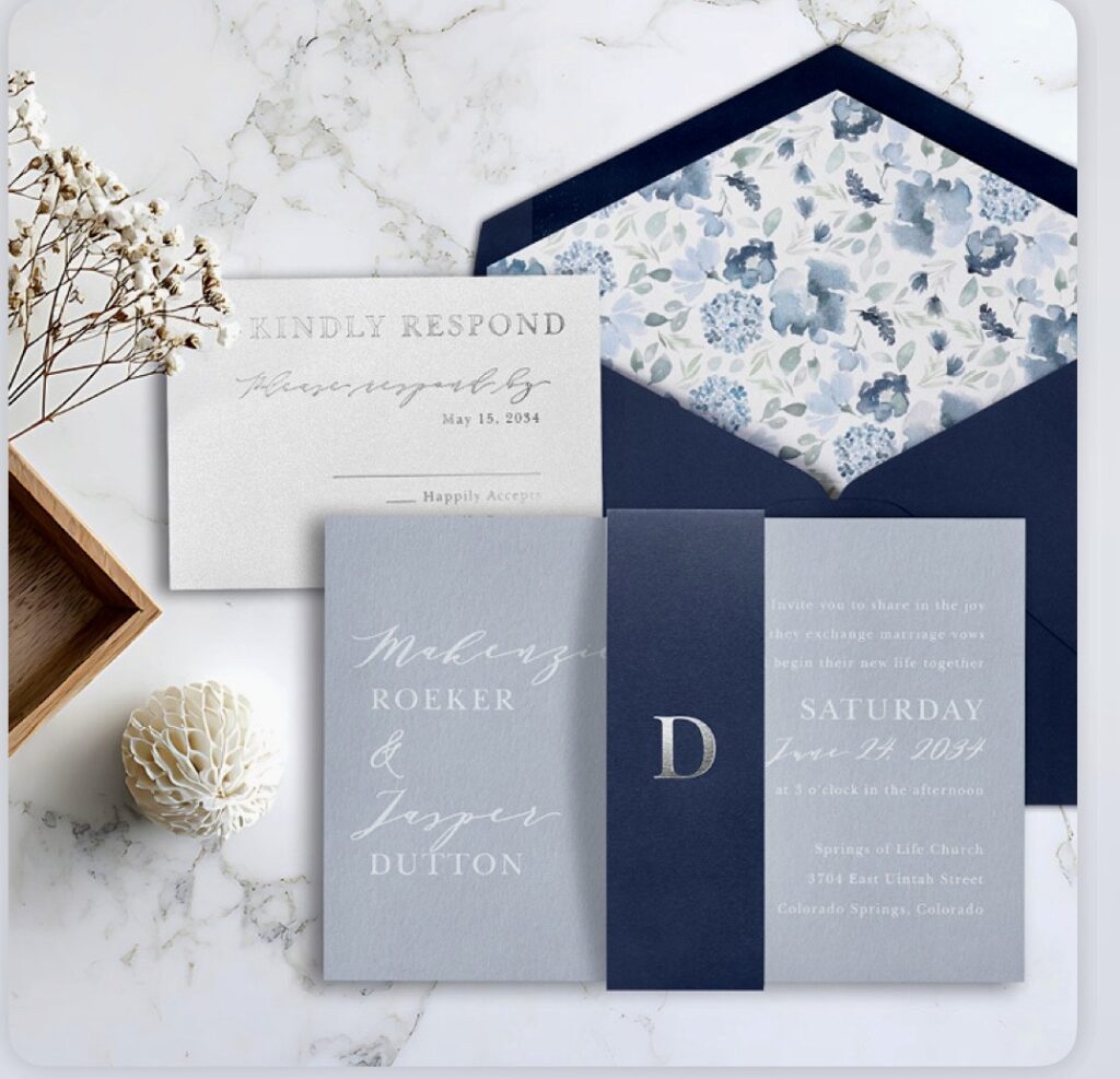 Makenzie and Jasper Blue Gray Invitation Suite, laying on marble table.
